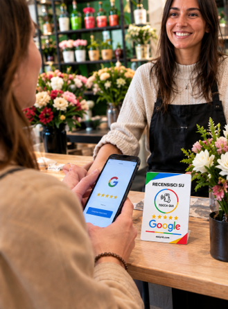 Cliente mostra la recensione lasciata dal telefono alla titolare di un negozio di fiori